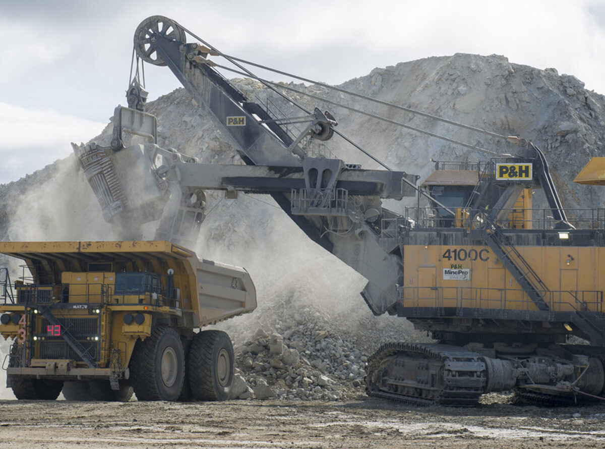 Heavy machinery working with mounds of rubble. Dust is seen surrounding the vehicles.