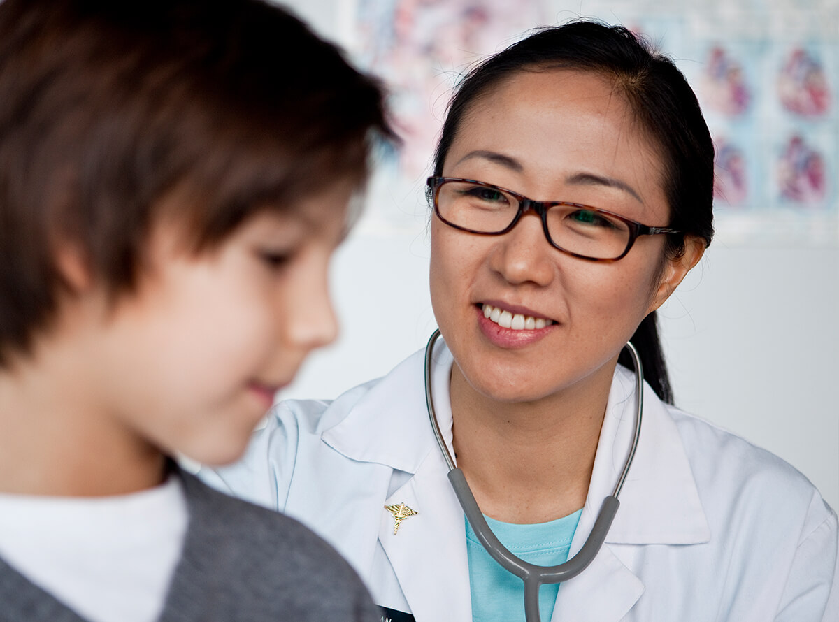 A doctor smiles at her patient, a young boy.