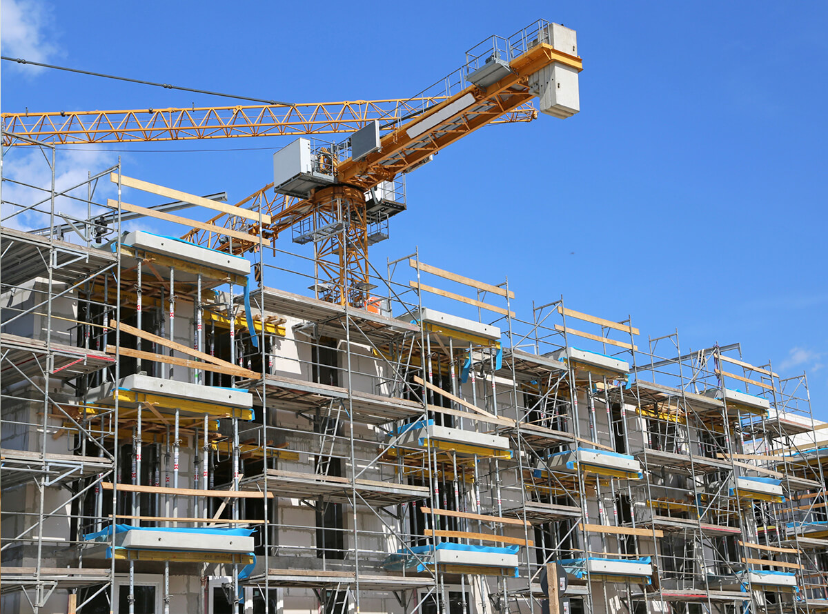 A crane is seen above a building in construction on a sunny day.