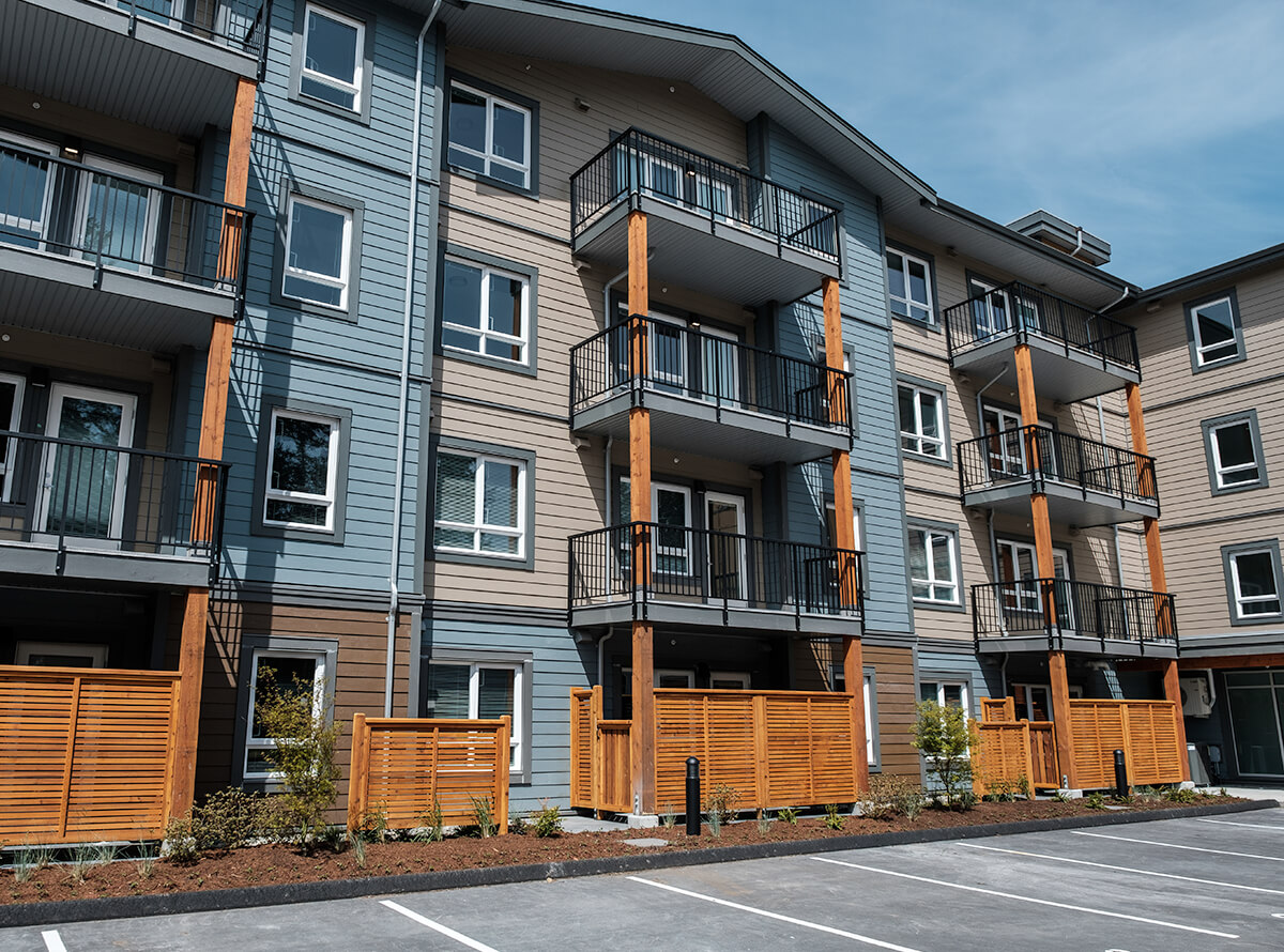 A four story residential complex with alternating wood panels of blue and beige.