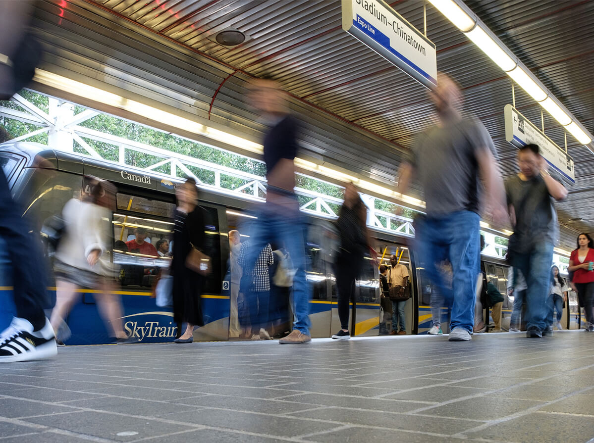 Blurred shot of people leaving a skytrain at Stadium-Chinatown station in Vancouver. View is from the floor looking up.