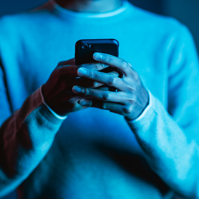 Person holding a smartphone in dim blue lighting