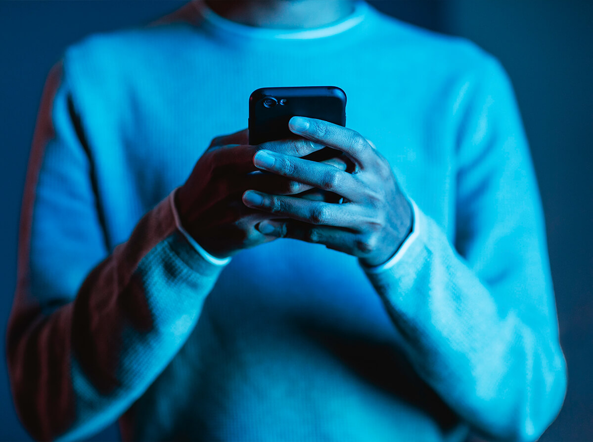 Blue-lit image of someone holding their phone with both hands.